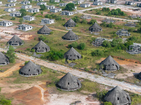 Aerial view of abandoned cone-shaped buildings in a construction project overgrown with grass and vegetation in Karangan, Kedah, Malaysia.