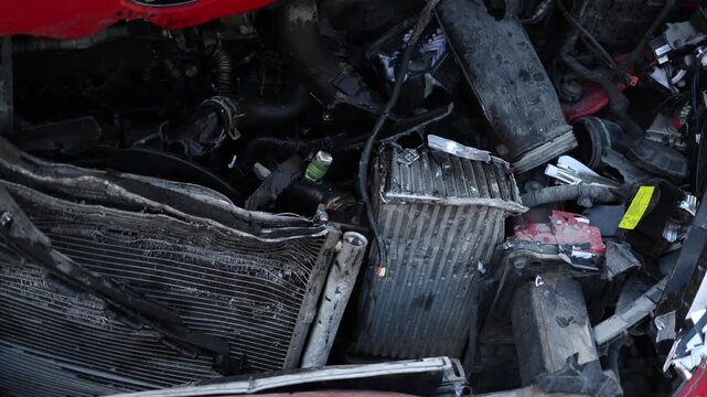 Close up of the crushed front section of an automobile following a road crash revealing a destroyed engine compartment broken parts and major structural collision damage