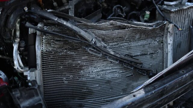 Detailed close up of extensive crash damage on the front of a vehicle with exposed engine components shattered parts and crushed bodywork after a powerful collision