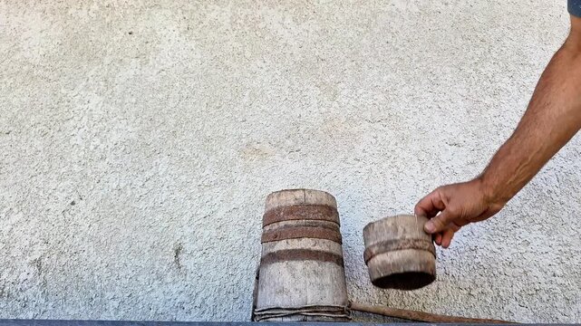 Wooden butter churn being used by hand to process cream into fresh homemade butter. Close-up of a rustic dairy-making tool and the manual churning process in a simple setting