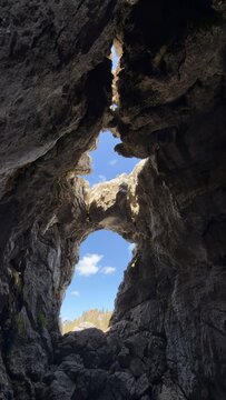 Dramatic view from inside a deep rocky cavern with cloudy blue sky above