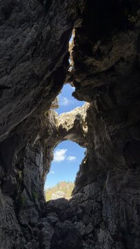 Unique limestone cave formation with blue sky view in rugged mountain wilderness