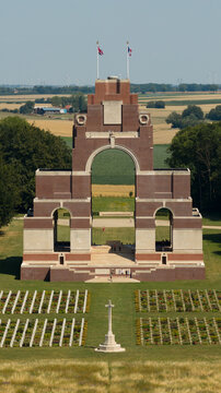 Aerial view of Thiepval Memorial with its brick arches, surrounded by the war cemetery with rows of headstones and a central cross, set against rural fields in Authuille, Hauts-de-France, France.