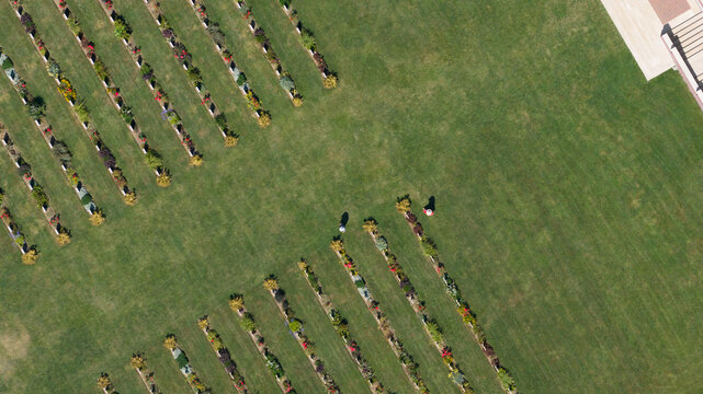 Aerial view of the Thiepval Memorial cemetery with rows of headstones set in manicured grass and two people walking through the grounds in Authuille, Hauts-de-France, France.