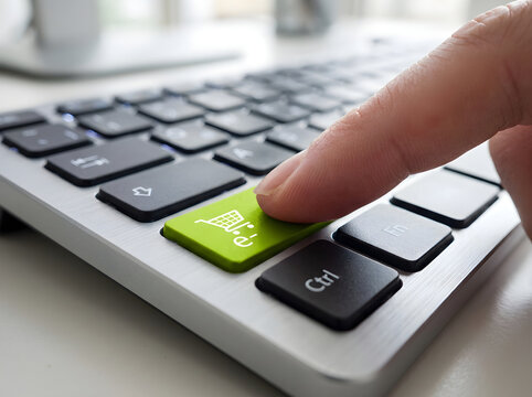 Person pressing a bright green shopping cart button on a computer