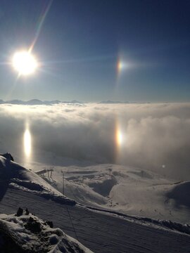 Sun dog halo beside the sun above a cloud inversion in the Alps