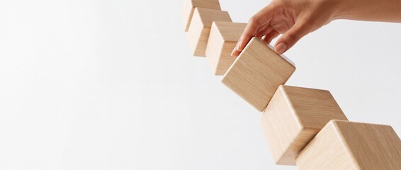 Fototapeta premium A business person's hand arranging wooden cubes in a diagonal line against a white background, representing growth, strategy, building a foundation, and a perspective shift in development.