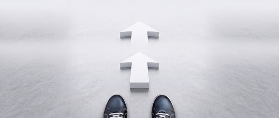 Fototapeta premium High angle point of view shot of person standing in front of two white arrows on grey floor, representing progress, direction, decision making, perspective shift, and future career movement.