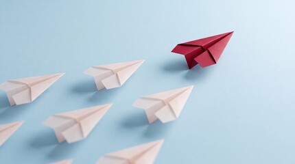 Fototapeta premium Concept of leadership and individuality represented by a single red paper plane leading a group of white paper planes on a blue background, symbolizing business strategy, vision and success.