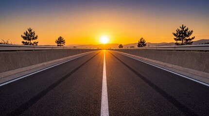 Fototapeta premium Empty asphalt highway road stretching towards a bright glowing sunset on the horizon at golden hour, scenic path through a rural landscape representing journey, freedom, and future goals.