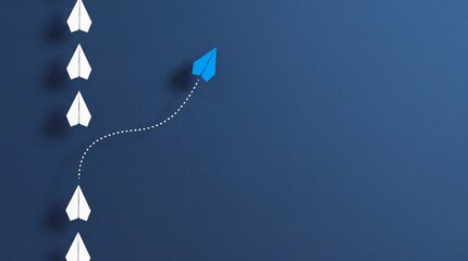 Fototapeta premium Overhead View of a Blue Paper Airplane Changing Direction and Deviating from a Group of White Airplanes on a Blue Background, Representing Unique Leadership, Innovation, and Business Strategy.