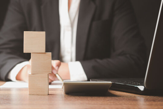 Businessperson working at desk with stacked wooden blocks  
