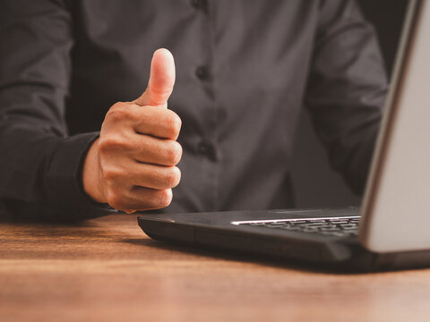 Woman giving thumbs up while working on laptop  