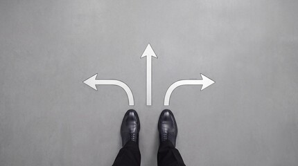 Fototapeta premium Top Down View of Businessman in Formal Black Leather Shoes Standing on Gray Ground with Three Directional Arrows Symbolizing Career Choices, Decision Making, and Future Path Direction Strategy.