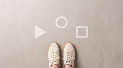 Fototapeta premium Top view of a person wearing white sneakers standing in front of white geometric shapes like triangle circle and square on gray concrete ground representing choice decision and career path