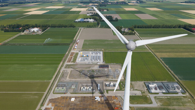 Aerial view of the Westermeerdijk wind turbine and electrical substation surrounded by vast agricultural fields in Espel, Flevoland, Netherlands.