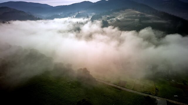 Aerial hyperlapse of dense morning fog rolling over mountain valley with houses