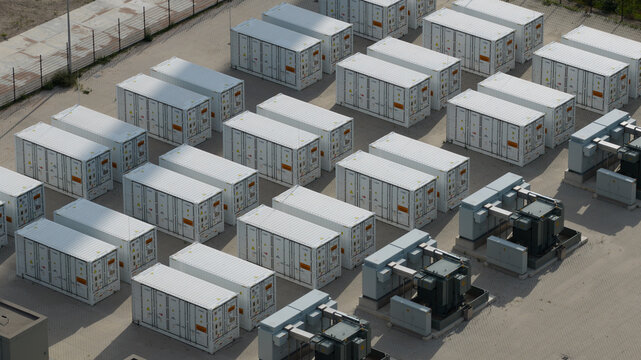 Aerial view of rows of white energy storage containers and electrical transformers at an industrial site in Dronten, Flevoland, Netherlands.
