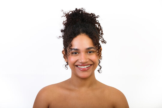 Smiling woman with curly hair promoting skincare and beauty products