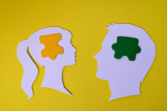 Conceptual composition with two human silhouettes facing each other with a differently colored piece inside the head, representing thought, human relationships, communication, connection, and differen