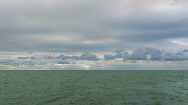 Sunbeams breaking through dark storm clouds over open sea
