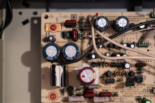 Electronic circuit board with capacitors and wiring inside a disassembled audio amplifier component chassis.