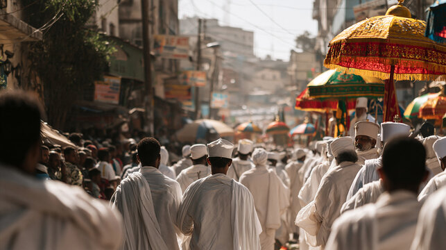 Ethiopian Orthodox community members wearing white traditional clothing walking through a sunny street during a festive religious procession with colorful umbrellas.