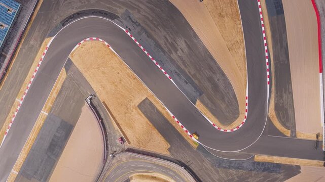 Yellow Race Car Navigating a Sharp Curve on an Asphalt Track