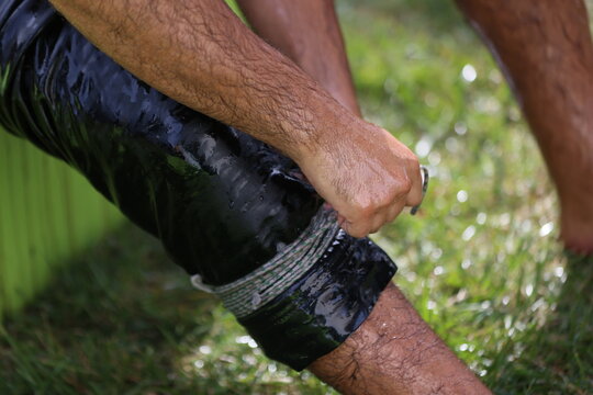 Traditional Turkish oil wrestling wrestler preparing and wearing his leather kispet before a competition. Close-up details of the wrestler's hands, legs and traditional wrestling attire during prepara