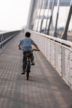 Young boy riding bicycle on long bridge