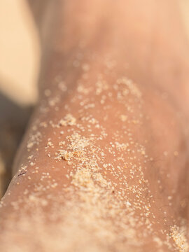Close up of sunlit skin covered with fine sand