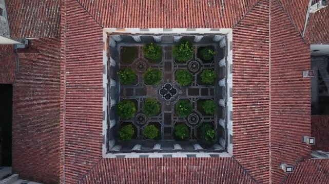 Top down aerial view of a cloister garden with geometric box hedges inside the Certosa di San Lorenzo monastery in Padula, Campania, Italy