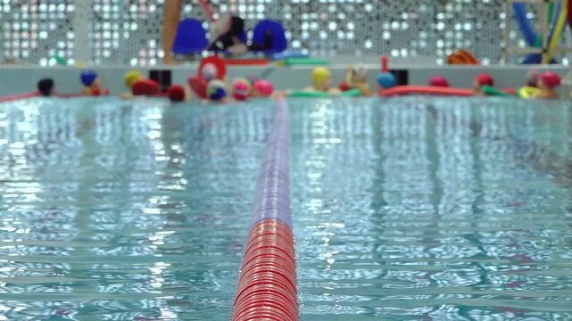 Bright multicolored foam pool noodles frame an indoor swimming pool, with sparkling water, colorful equipment, and decorative lights creating a playful atmosphere and copy space.
