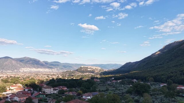 Aerial view of the Vallo di Diano valley at golden hour with a hilltop town in the distance and wooded mountain slopes, Salerno, Campania, Italy