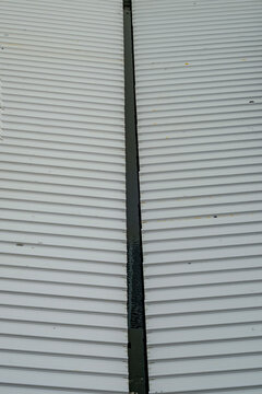 Corrugated metal roof panels with central drainage gutter in industrial building