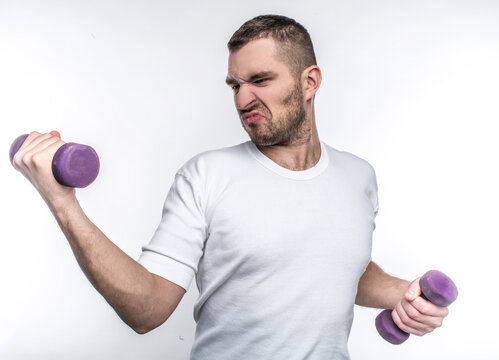 Thin guy is holding dumbbells in his hands. He is trying to gain some muscles before summers will come. He wants to start to go to fitness club. Isolated on white background.