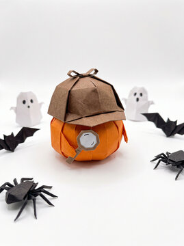 Origami pumpkin detective with magnifying glass and spiders
