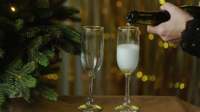 New year eve party. Female hands pour champagne or white sparkling wine into a glass