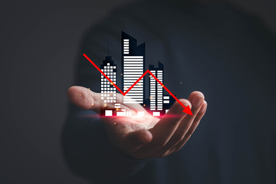 Business decline concept showing a hand holding a digital cityscape with a falling arrow, symbolizing economic downturn, market decline, financial risk, recession, loss, and investment challenges.