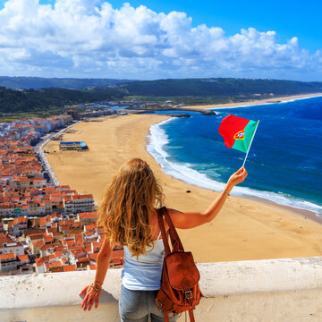 woman tourist holding portugal flag looking at beautiful beach view travel concept