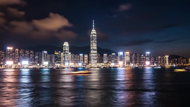 Boats move in the water as the sun sets behind the tall buildings of