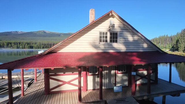 Boathouse standing on Maligne Lake with kayaks on dock reflecting surrounding mountains and evergreen forest in Jasper National Park summer sky, highlighting Canadian nature tourism in Alberta, Canada