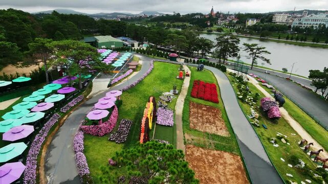 Aerial view of colorful garden rows and umbrellas along lush riverside walkway