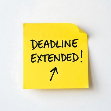 A bright yellow sticky note with handwritten text deadline extended and an arrow pointing upward against a white surface