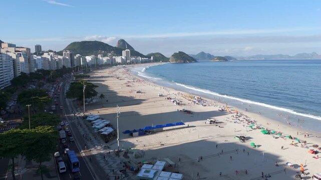 Aerial flyover of Copacabana Beach with Sugarloaf Mountain in the background on a sunny day, Rio de Janeiro, Brazil.