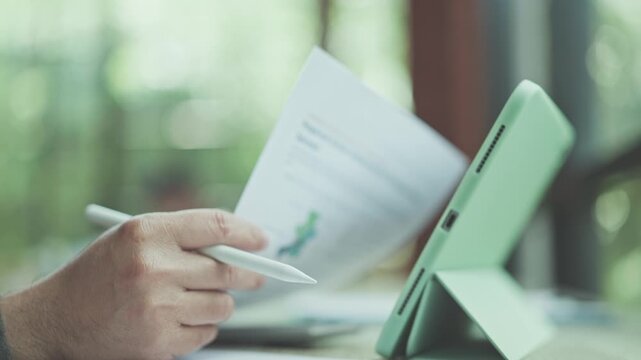 Manager conducts analysis market data, holding stylus pens aid analysis beside digital tablet as finance analysis proceeds in office.