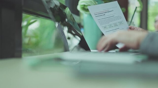 Hands conduct audit research over sustainability reports, reviewing energy audit metrics alongside corporate audit documentation climate infrastructure investments.