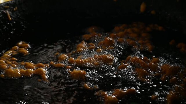 Delicious pakora snack frying deeply in boiling hot oil pan. It is a popular South Asian deep-fried snack made of vegetables, paneer coated in a spiced batter typically composed of gram flour, spices.