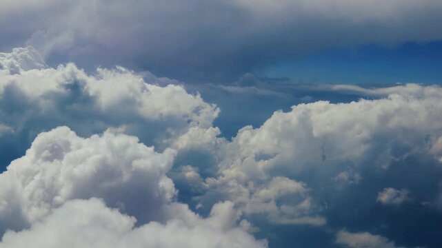 Flying through a majestic cloudscape with cumulus clouds and blue skies, offering a serene and beautiful aerial view.