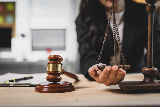 Lawyer's hands balancing scales of justice, representing legal equality, fairness, and law firm consultation. Gavel on table.